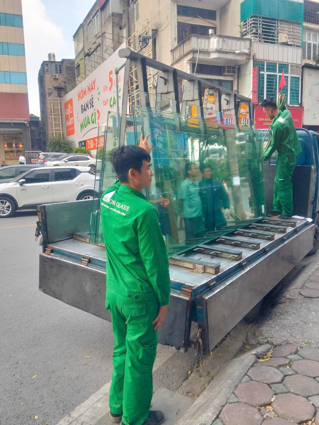 Nhân viên phối hợp chuyển kính từ xe đến khu vực công trình